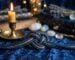 Un noeud symbolique en cordon naturel dispose sur un velours sombre pres d une bougie, tons or et bleu nuit