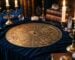 Vieille roue astrologique gravee dans le laiton patine sur un velours bleu nuit, lueur de bougie, symboles flous